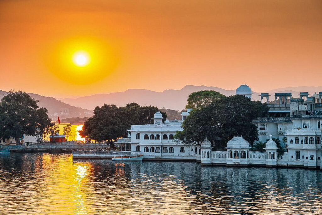 Top 7 Unique Travel Destinations to Visit in 2025 Udaipur's majestic palaces surrounded by a glistening lake with a red sky approaching sunset overhead