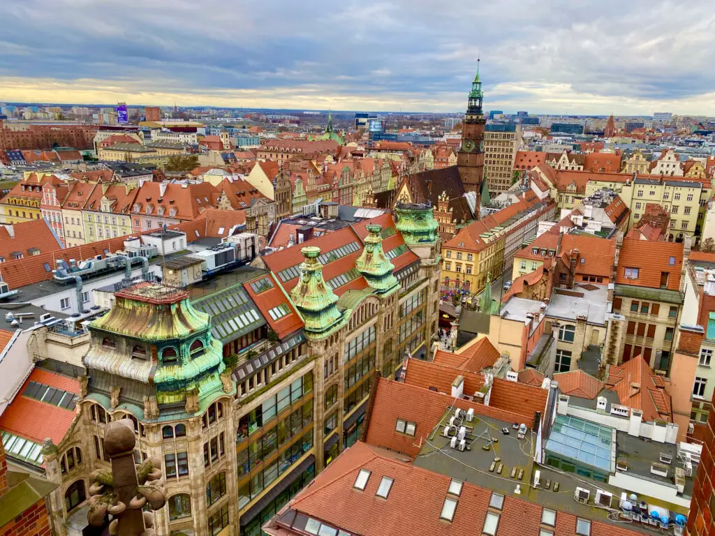 Top 7 Unique Travel Destinations to Visit in 2025 An aerial view of Wroclaw, Poland, showcasing its historic architecture, charming red rooftops, and unique green copper accents on buildings, with the iconic town hall and market square in the distance —one of 2025's unique travel destinations.